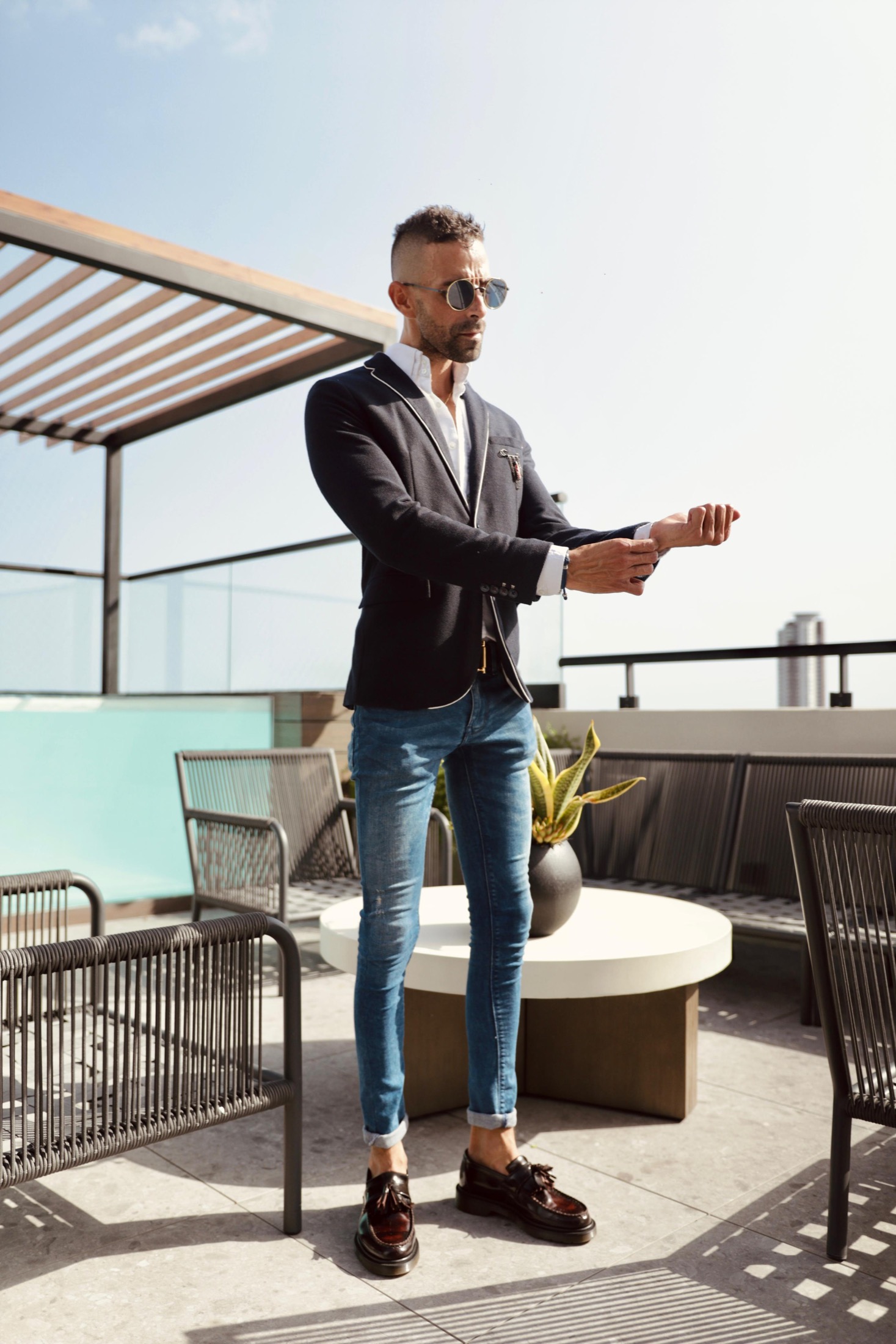 Ángel Báez vistiendo atuendo elegante en una terraza luminosa